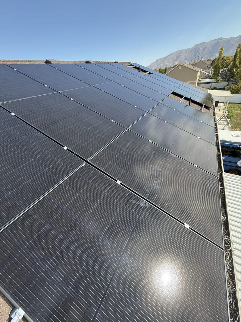[Trina panels] Close-up of solar panel array and racking hardware with clear sky, sun glare on one panel