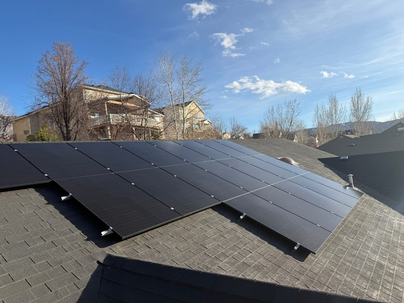 [black-on-black Trina panels] Beautiful residential solar installation with clear blue sky and landscape backdrop showing completed system.