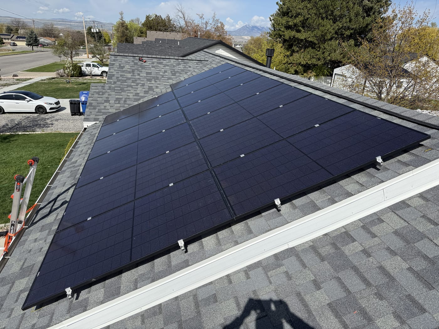 [black-on-black panels] Top-down view of solar array on gray shingle roof