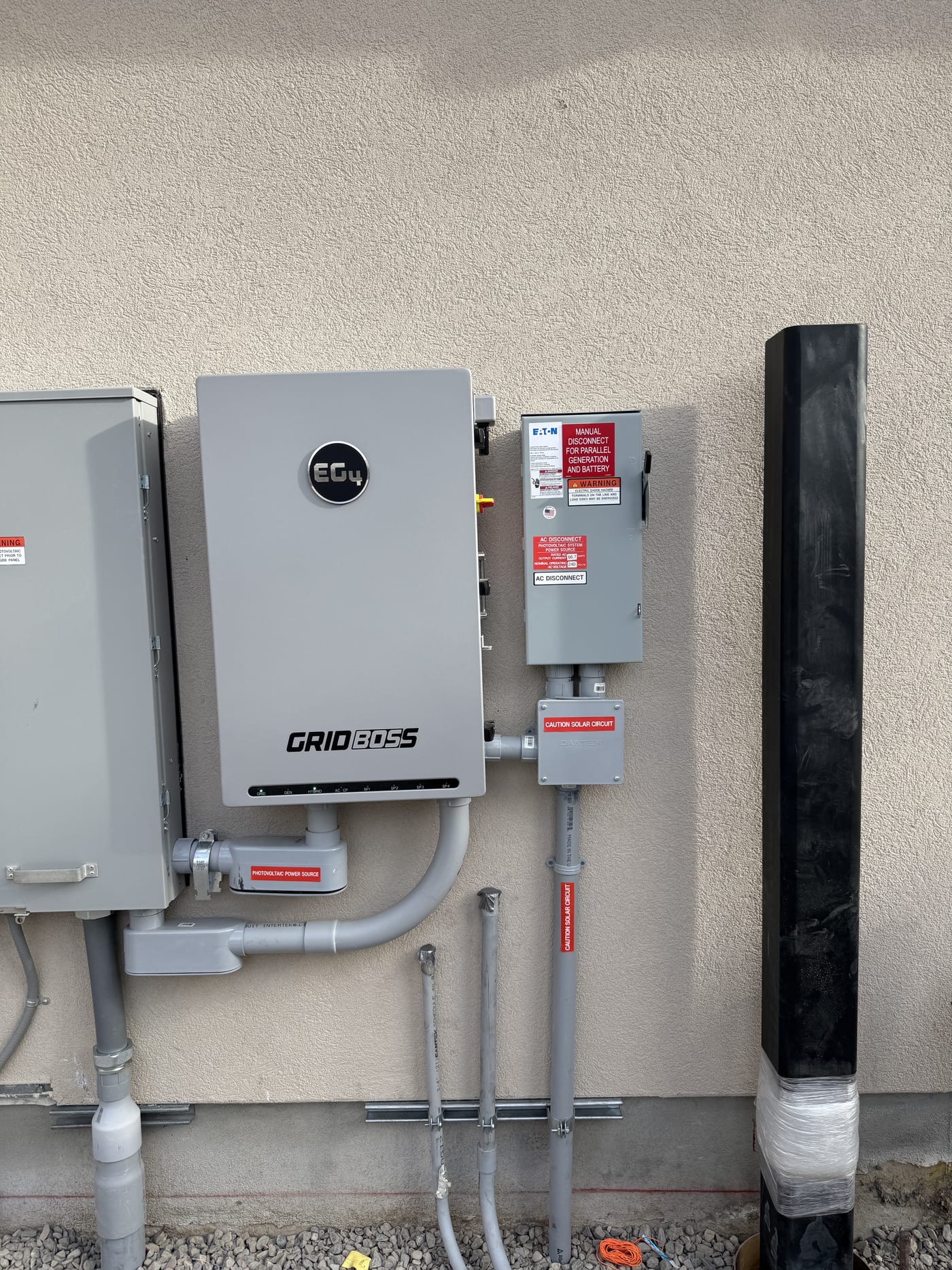EG4 GridBOSS inverter with AC disconnect conduit and caution labels mounted on exterior wall