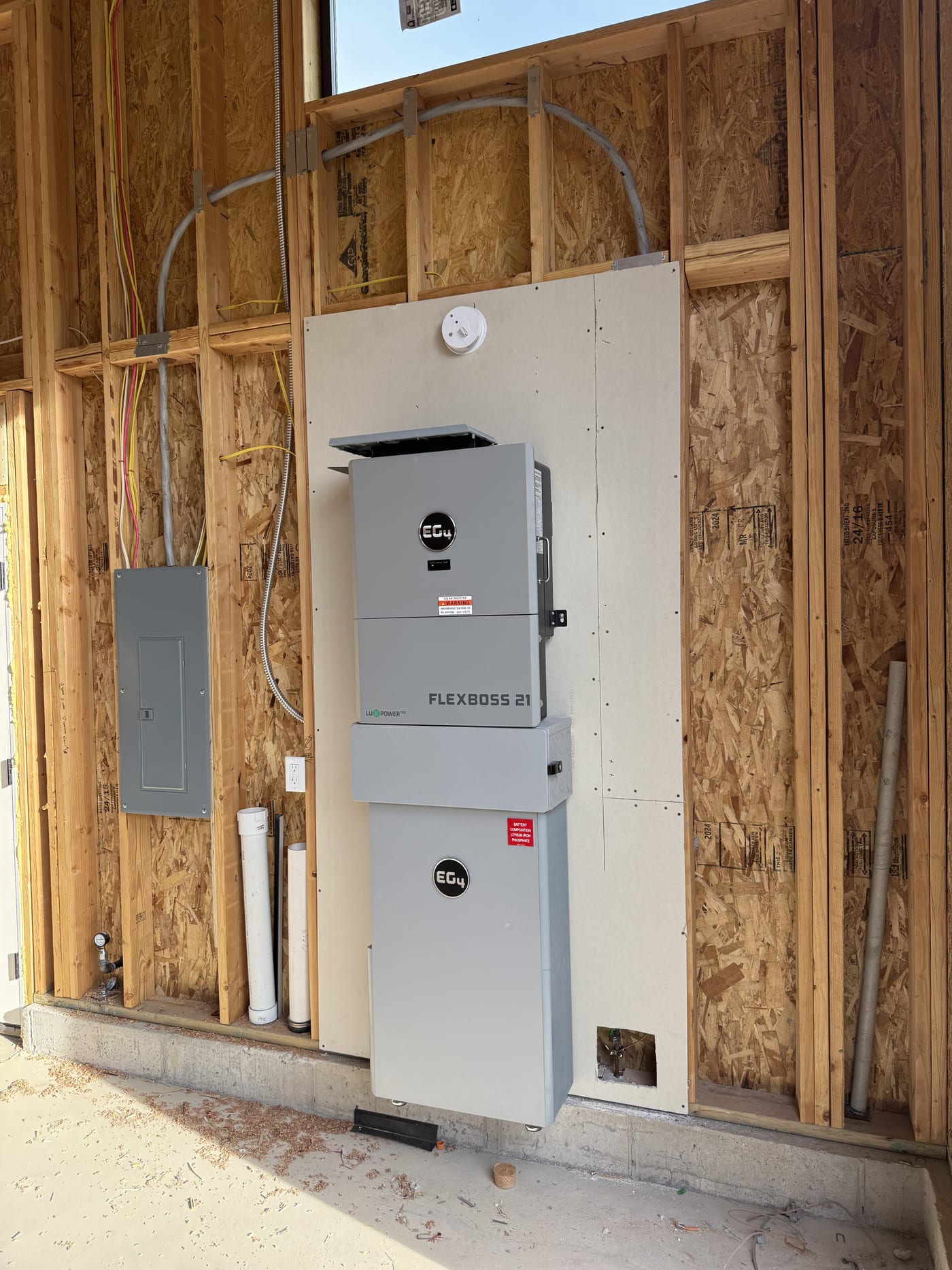 EG4 FlexBOSS 21 battery system mounted on wall with sub-panel in garage