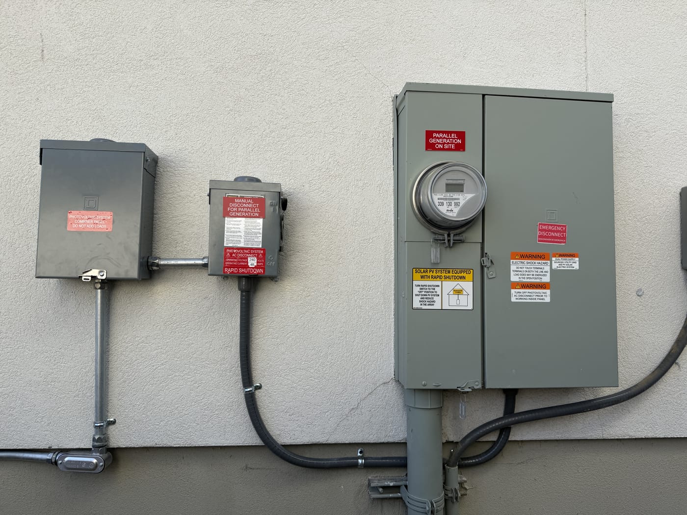 Meter base electrical panel and disconnect with warning labels and conduit on stucco exterior wall