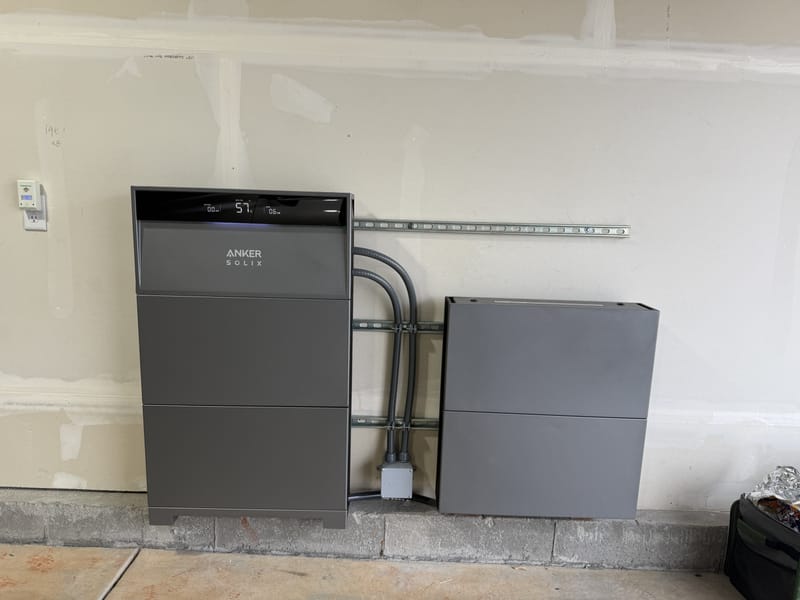 Anker Solix X1 battery system with two stacked units (inverter left, battery right) showing 15 percent charge on basement utility room wall