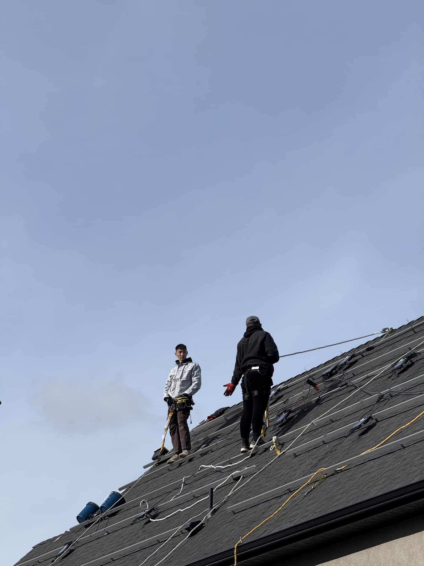 Crew members on roof handling wiring along racking rails, shot from roof level