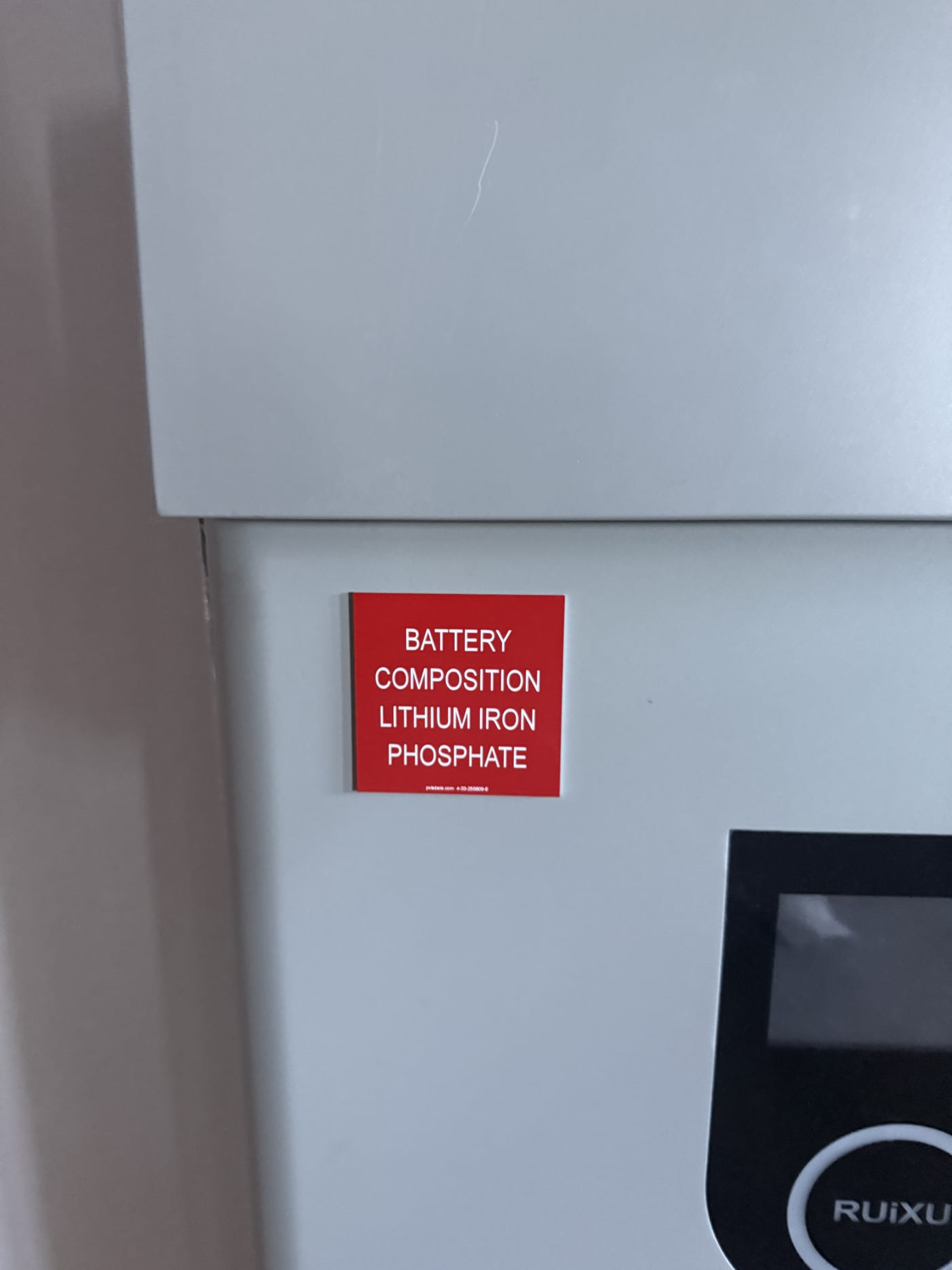 RUiXU inverter and battery unit wall-mounted in garage/utility room with electrical panel above, new construction
