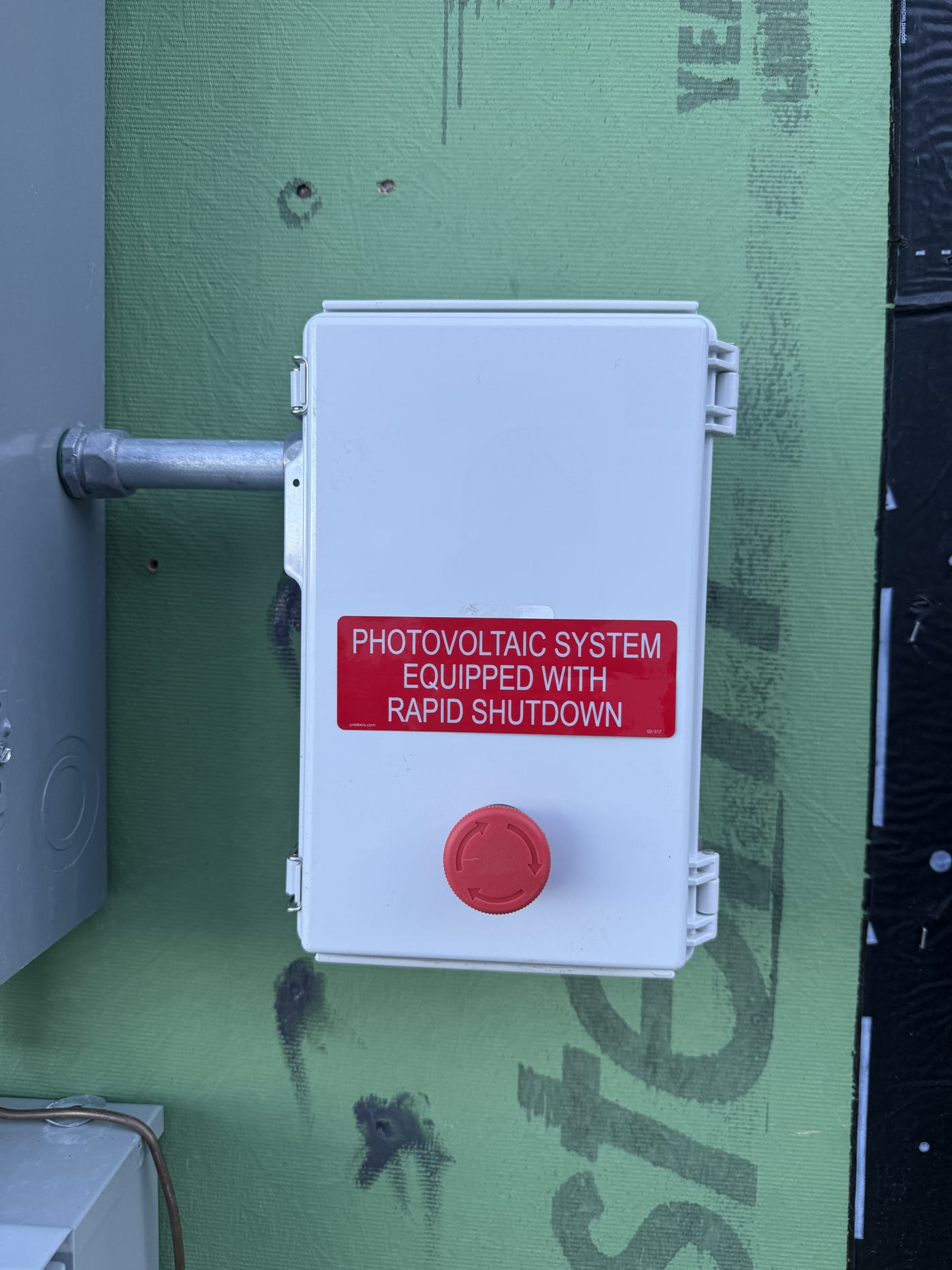 Exterior meter socket with exposed CT connections, rapid shutdown and warning stickers, on green ZIP sheathing (new construction)
